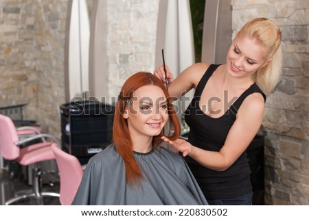 Happy redhead woman getting new haircut. Beautiful blond hairdresser giving new haircut to redhead female
