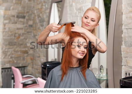 Happy young woman getting a new haircut. Beautiful young hairdresser giving new haircut to female customer at parlor