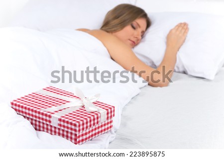 Asleep woman has surprise present waiting for her in bed. beautiful young woman sleeping on bed with presents