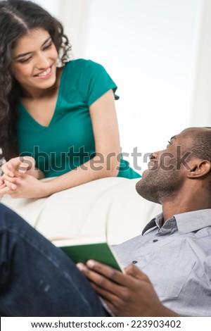 Couple in living room talking while sitting on sofa. profile of black african man sitting on sofa and looking at woman