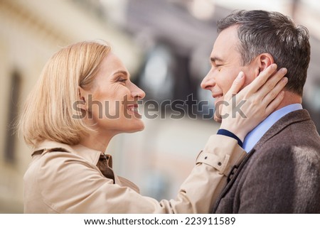 Portrait of amorous couple touching faces and laughing. blond woman looking at man and smiling