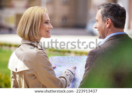 beautiful elegant mid age couple resting outdoors. woman holding map and showing man address