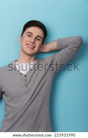 Excited man isolated over blue background. Handsome young man smiling in casual standing against wall