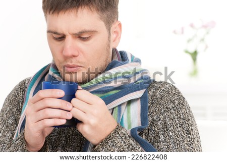 closeup on man on sofa drinking hot tea. young man holding cup on sofa in living room
