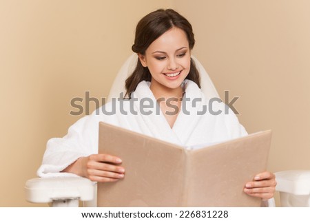 Young woman receiving pedicure in hairdressing salon. Woman sits in hairdress salon and reading