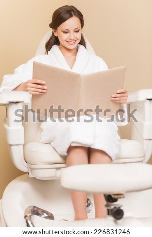 Young woman receiving pedicure in hairdressing salon. Woman with hair color samples sits in hairdress salon