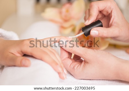 Woman in nail salon receiving manicure by beautician. closeup of female hand resting on white towel