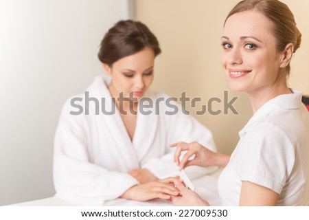 Close-up of beautician hand filing nails of woman in salon. manucurist women sitting in spa salon and looking at camera