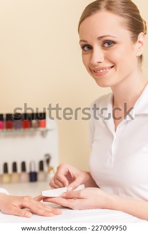 Close-up of beautician hand filing nails of woman in salon. manucurist women sitting in spa salon and smiling at fingers