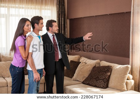 man real estate agent showing couple new house. male agent showing view from window on city