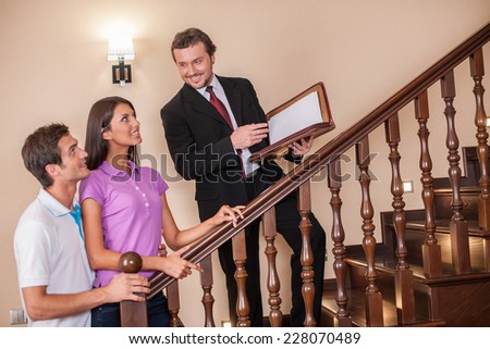 Estate agent with young couple on ladder. three going up to second floor on wooden ladder to see house