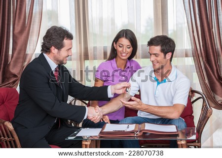 closeup on happy man taking keys to new house. agent giving keys to young couple purchasing new house and shaking hands