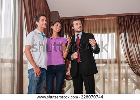 man real estate agent listening to woman client in new house. male agent showing view from new house window
