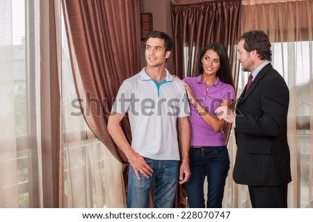 man real estate agent showing couple new house. male agent showing view from new house window