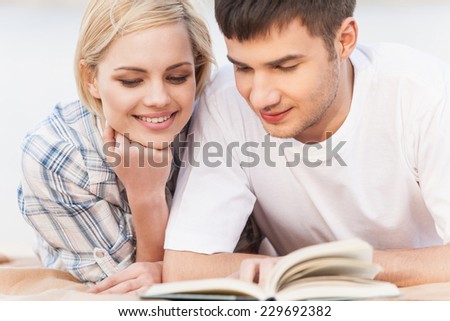 Portrait Of Happy Couple Reading Book On Summer Beach. Couple reading book on lake shore