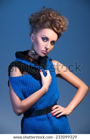beautiful blonde woman wearing blue dress on blue background. knitted dress without sleeves on pretty girl