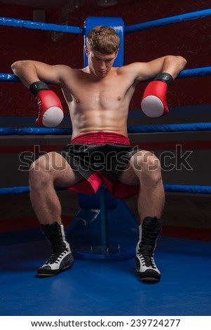 Handsome muscular young man wearing boxing gloves. waist up of boxer man looking down
