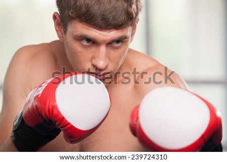 Handsome muscular young man wearing boxing gloves. close up of boxer man looking away
