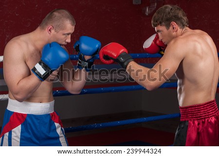 Strong boxer and his opponent during box fight in ring. Sport and people, two men exercising and fighting in boxing gym