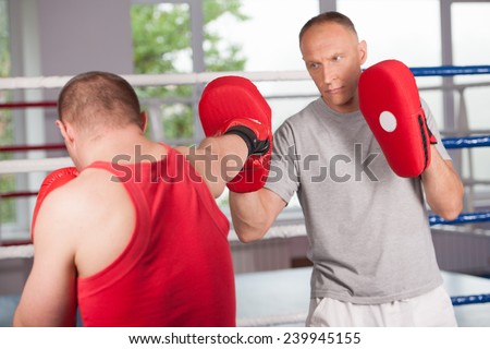 boxer and his coach doing some sparring in ring. Boxer and his coach practicing some moves