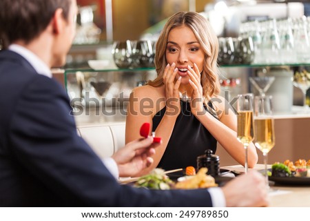 Beautiful couple having romantic dinner at restaurant. back view of man proposing to woman in restaurant