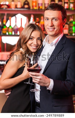 Young happy couple romantic date. man and woman holding wine and standing in restaurant