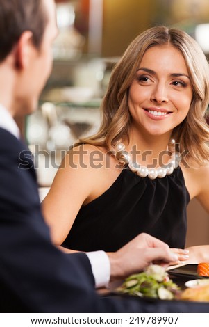 Beautiful couple having romantic dinner at restaurant. smiling woman looking at man at cafe sitting at table