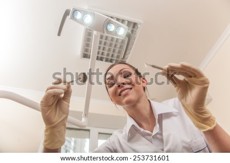 Portrait of lovely dental assistant with toothy smile. dentist doctor holding tools and looking into camera