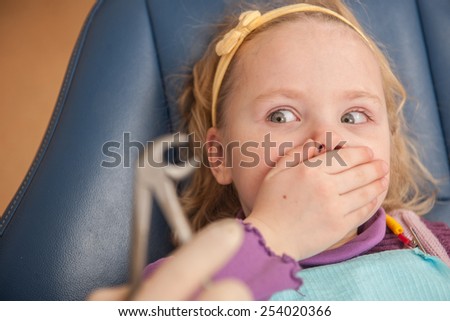 portrait of scared girl at dentist\'s office. dentist extracted tooth of little girl