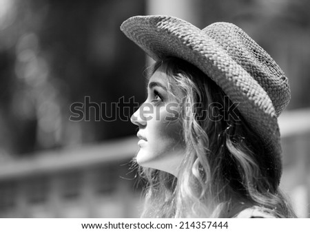 Black and white profile of a beautiful country girl with curly blonde hair wearing a cowboy hat looking up.
