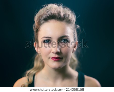 Portrait of a beautiful woman with blonde curly hair against black background.