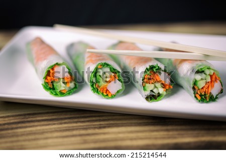 Summer roll sushi on a white rectangular plate with chopsticks.