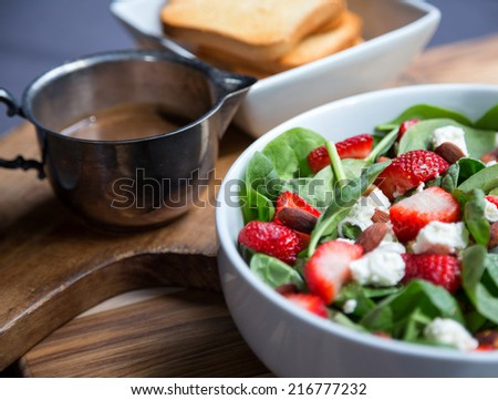 Spinach salad with strawberries, scallions, coconut toasted almonds, goat cheese, vinaigrette dressing and toast.