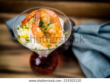 Shrimp and grits with cheese and chives in a martini glass.