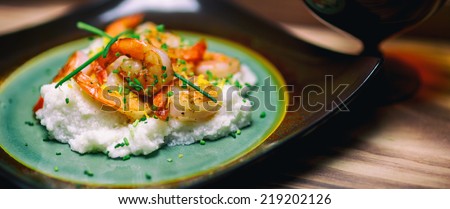 Shrimp and grits with cheese and chives on a rustic plate.