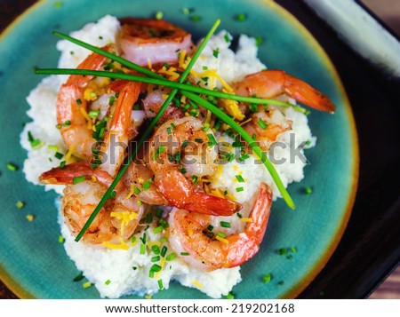Shrimp and grits with cheese and chives on a rustic plate.