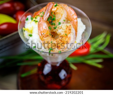 Shrimp and grits with cheese and chives in a martini glass.