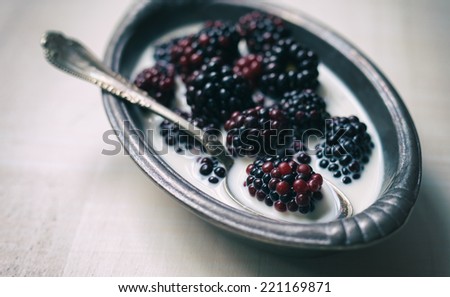 Blackberries and cream in a pewter dish with an antique sliver spoon.