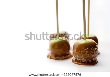 Four green caramel apples with sea salt, toffee and coconut sprinkles on parchment paper.