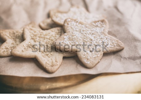 Several star shaped sugar cookies with sprinkles on kraft paper and wooden background. Vintage filter.