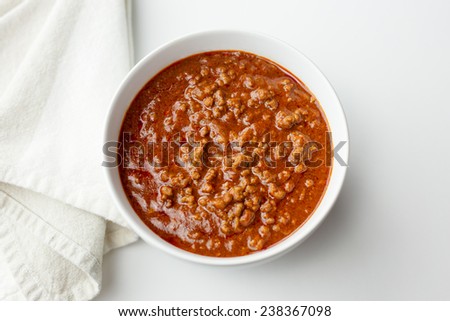 Bowl of chili with napkin on white background.