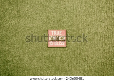 Olive green textured paper background with a pink square tag reading \