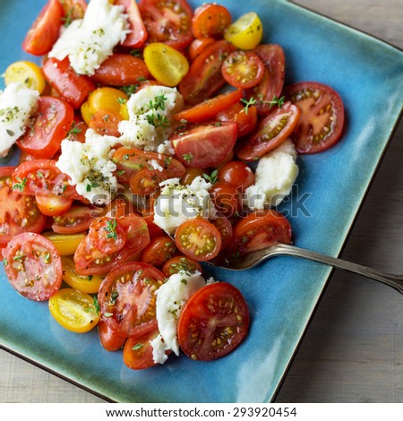 Fresh Caprese salad on a square turquoise plate.