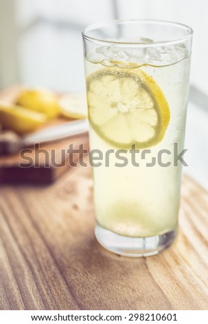 Glass of lemonade near a sunny widow.  Garnished with a slice of lemon.  Vintage filter.