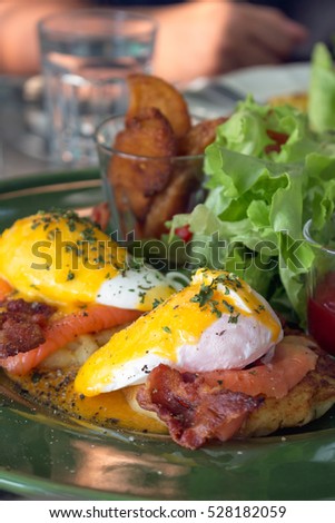 Eggs benedict with smoked salmon and bacon on a toasted bun,