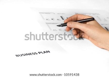 paper on desk with business plan on it. hand holding pen. paper with graphics on the background.