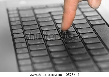close up of a black keyboard with a person\'s hand typing on it. One finger