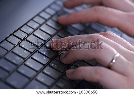 close up of a black keyboard with a person\'s hand typing on it
