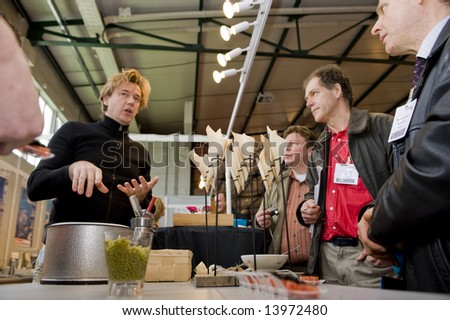 Brussels,Belgium, LABORAMA fair - march 13: People watch as a man explains about cooking with chemical appliances.  The Fair is an annual event, intended for people in the chemical industry.