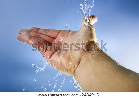 human hand splashing cool water on blue background
